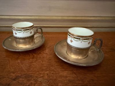 two cups and saucers sitting on a table next to each other