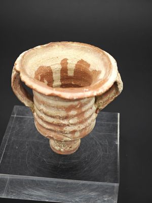 une image représentant un vase en argile posé sur un socle transparent