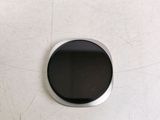 a black button on a white surface with a white background