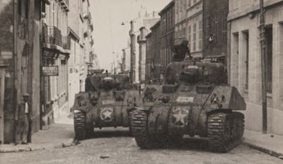 a black and white photo of a couple of tanks on a city street
