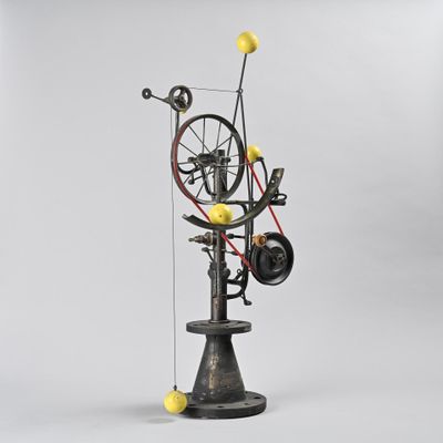 a sculpture of a spinning machine with yellow balls on top of it