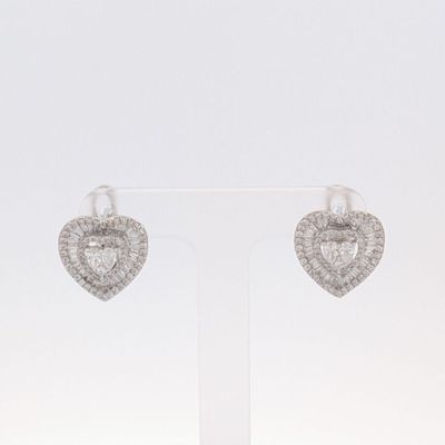une paire de boucles d'oreilles en diamant en forme de cœur, présentées sur un présentoir