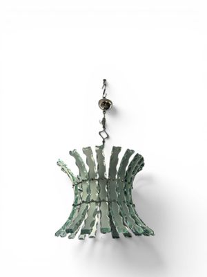 a green lamp hanging from a chain on a white wall