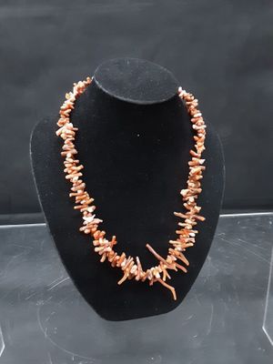 a necklace made out of coral beads on a black display case
