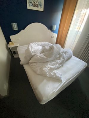a white bed in a small room with a blue wall