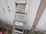 une échelle appuyée contre un mur, à côté d'une borne d'incendie