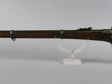 a rifle with a wooden barrel on a stand on a white surface
