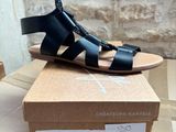 a person holding a pair of sandals on top of a box