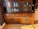 a wooden china cabinet with a glass door on top of it