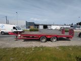 une remorque à plateau rouge garée sur le bord de la route