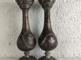 two metal vases sitting on a table next to a wall
