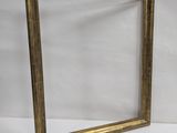 a gold frame sitting on a white surface next to a white wall