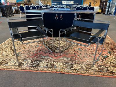 plusieurs chaises et une table dans une pièce dont le sol est recouvert d'un tapis