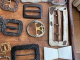 a lot of belts and buckles on a wooden table