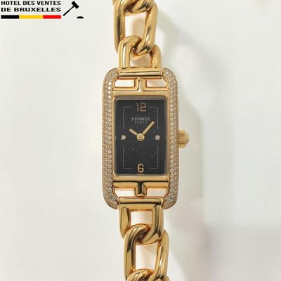 une montre-bracelet en or avec un cadran noir sur fond blanc