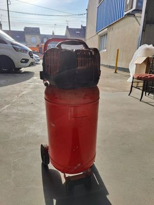 a red air compressor sitting on a cart in a parking lot