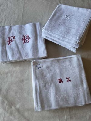 three white towels with red letters on them sitting on top of a bed