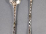 two silver spoons and a spoon with a handle on a gray surface