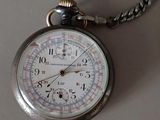 a silver pocket watch on a chain on a table
