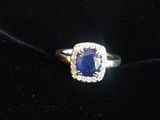 une bague sertie d'un saphir bleu et de diamants, posée sur un fond de velours noir