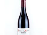 the bottle of red wine is sitting on a white surface