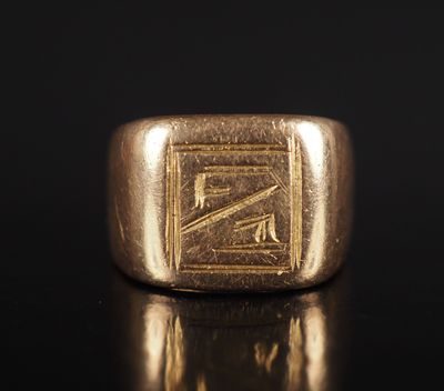 un gros plan d'une bague chevalière en or posée sur une surface noire