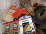a pile of toys and a doll house on a bed
