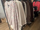 clothes hanging on a rack in a clothing store next to a window