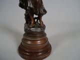 bronze statue of a woman holding a dog on a pedestal
