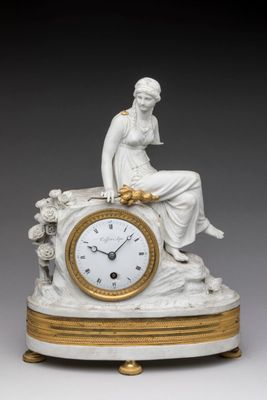 une horloge blanche et dorée sur laquelle est assise une femme