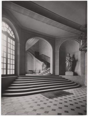 photographie en noir et blanc d'un escalier dans un immeuble où se trouve une statue