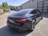 the rear end of a black car parked in a parking lot