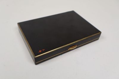 une petite boîte noire aux bords dorés posée sur une table blanche