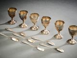 Plusieurs cuillères en argent sont alignées sur une table