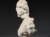 a white sculpture of a woman holding a child on a wooden base