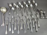 a lot of silver spoons and forks laid out on a table