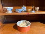 many bowls and cups on a wooden shelf in a room