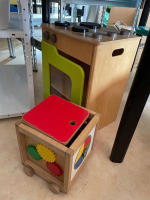 a small kitchen with a wooden table and a colorful play kitchen