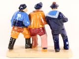 three figurines of three men sitting on a bench