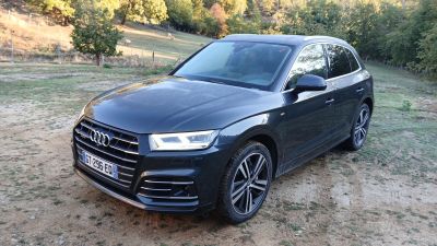 Le SUV Audi noir est garé sur la terre battue, dans le champ.