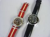 deux montres posées sur une surface blanche ; l'une est rouge et l'autre présente une bande jaune et blanche