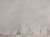 bedspread with a white ruffled design on top of it