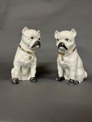 paire de figurines de chiens blancs avec des colliers dorés sur fond gris