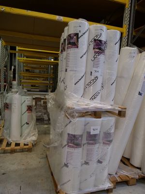 many rolls of paper sitting on pallets in a warehouse