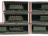 six green train cars in a box on a white surface