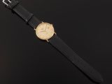 a gold wrist watch with black leather strap
