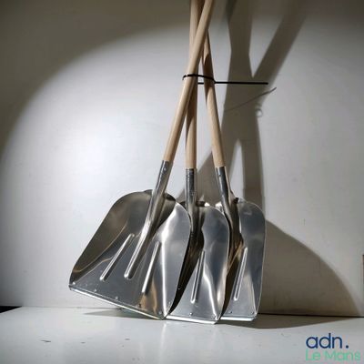 three shovels that are hanging on a wall