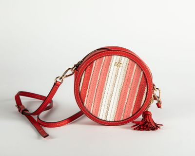 a red round purse with a tassel on a white background