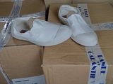 une paire de chaussures blanches posée sur une pile de cartons