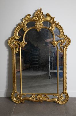 un miroir doré posé par terre devant un mur blanc